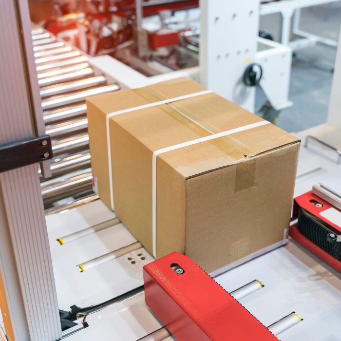 cardboard box of product packaging is moving on conveyor belt of automatic packing machine in the manufacturing factory